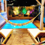 Piscine de nuit devant un hamac